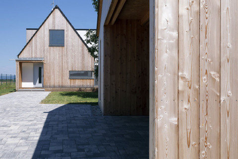 Garážové stání a dům jsou architektonicky sladěny a propojeny betonovou zámkovou dlažbou. Hlavní vchodové dveře jsou chráněny dřevěným závětřím