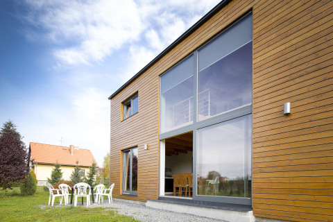 Kompaktní fasáda s velkoformátovými okny a modřínovým obložením spojuje moderní design s tradiční architekturou