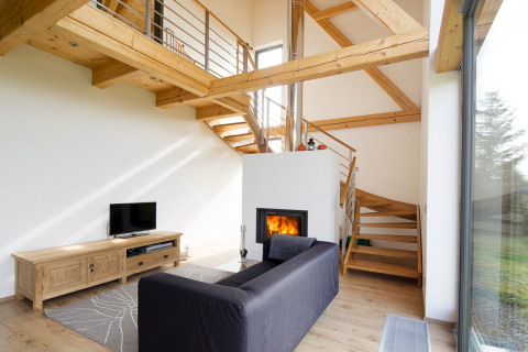 Otevřené schodiště vede přímo z obývacího prostoru na galerii v patře, kde jsou ložnice. Přiznaná dřevěná konstrukce vytváří – spolu s krbem – pocit „tepla domova“
