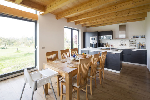 Decentní přírodní barevnou škálu interiéru doplňuje šedá – šedé nátěry dřevěných oken a kuchyňská linka s dvířky antracitového odstínu