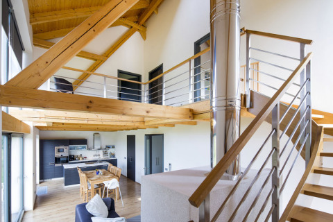 Základem domu je velký společný obývací prostor otevřený přes dvě podlaží až do krovu. Je tu jak sezení, tak i jídelna s kuchyní. Výtvarný koncept spočívá v kontrastu konstrukcí z přírodního dřeva a bílých stěn