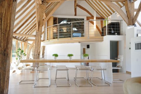 Prosklené plochy a bílý sádrokarton dávají vyniknout pečlivě renovované dubové konstrukci mohutného starého krovu. Z dubového dřeva je i podlaha a jídelní stůl, čiré plastové židle umocňují vzdušný charakter interiéru